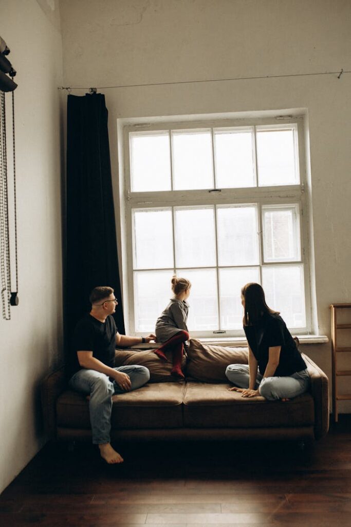 Casual family scene by a large window on a cozy couch, capturing a moment of leisure.